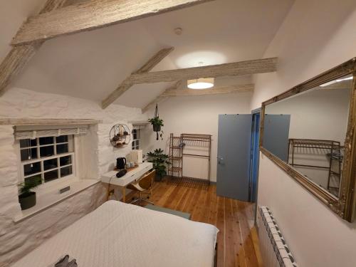 a bedroom with a bed and a desk and a mirror at Postmasters House in Helston