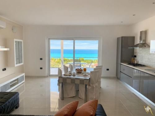 a kitchen with a table with a view of the ocean at VILLA ARCANGELO Lo in Mandatoriccio Marina