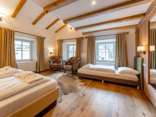 a bedroom with two beds and two chairs and windows at Biber Art Apartment 1 Small in Biberwier
