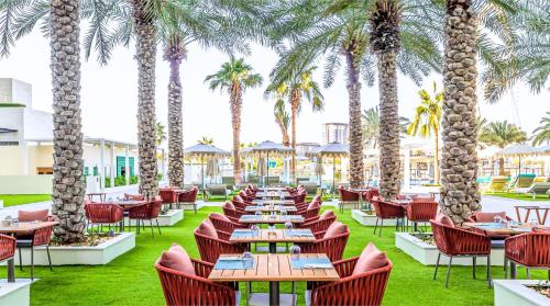 a restaurant with tables and chairs and palm trees at DoubleTree by Hilton Dubai Jumeirah Beach in Dubai