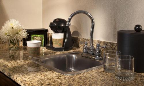 a kitchen counter with a stainless steel sink and cups at Embassy Suites by Hilton Flagstaff in Flagstaff