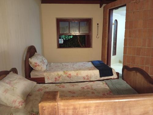 two beds in a room with a window at Casa Duque in Ribeirão Preto