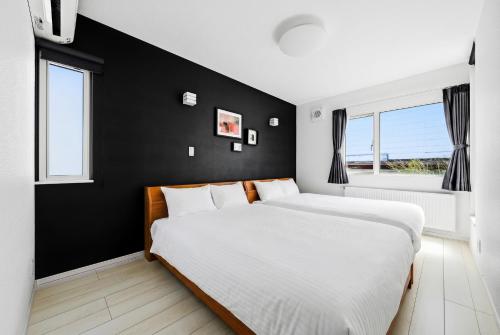 a bedroom with two beds and a black wall at Mist in Sapporo
