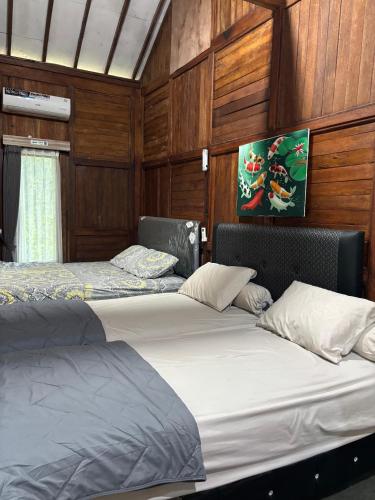 two beds in a room with wooden walls at NK Villa Syariah And Cafe Prigen in Pasuruan