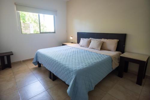 a bedroom with a bed with a blue comforter and a window at Suites Real Tabasco in Villahermosa