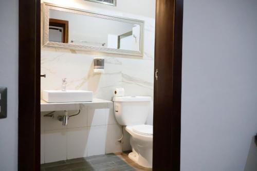 a bathroom with a toilet and a sink and a mirror at Hotel Maria Maria in Bacalar