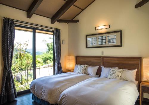 a bedroom with a bed and a large window at エンゼルグランヴィラ由布院 in Yufu