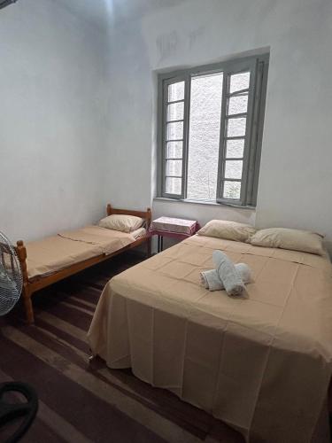 two beds in a room with a window at Hostel Bahia POA Próx Shopping Total, Rodoviária e Hospital Presidente Vargas in Porto Alegre