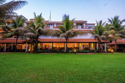 a building with palm trees in front of a yard at DoubleTree by Hilton Hotel Goa - Arpora - Baga in Baga