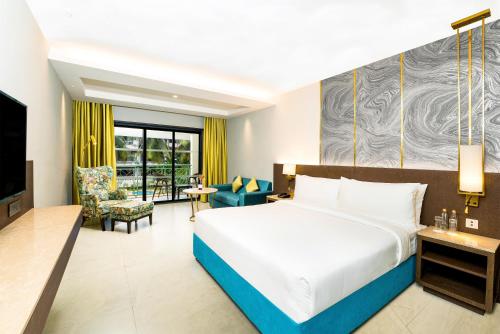 a bedroom with a large bed and a living room at DoubleTree by Hilton Hotel Goa - Arpora - Baga in Baga