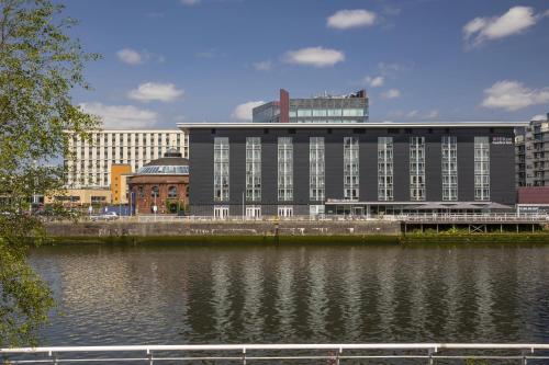 a large building next to a body of water at Hilton Garden Inn Glasgow City Centre in Glasgow