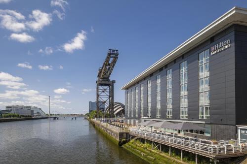 a building with a crane next to a river at Hilton Garden Inn Glasgow City Centre in Glasgow