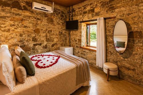 a bedroom with a bed and a stone wall at Casa Vêneto -Vale dos Vinhedos in Bento Gonçalves