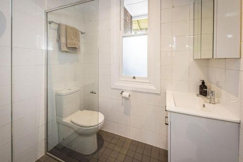 a white bathroom with a toilet and a sink at Centennial Cottage 1 - 'Boorool' in Bowral