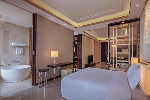 a bedroom with a large bed and a bath tub at Hilton Haikou in Haikou