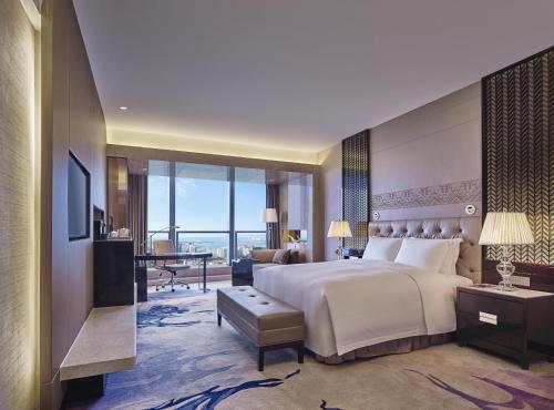 a bedroom with a large bed and a living room at Hilton Haikou in Haikou