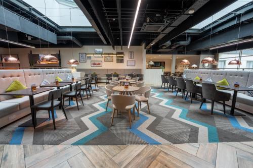 a restaurant with tables and chairs and a bar at Hampton By Hilton Bristol Airport in Redhill