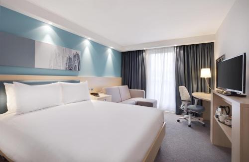 a hotel room with a bed and a desk and a tv at Hampton By Hilton Bristol Airport in Redhill