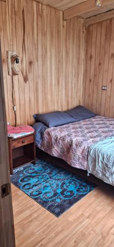 a bedroom with a bed and a table and a rug at Luz de mareas in Ancud