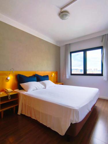 a bedroom with a large white bed and a window at BLUE HAT - Apart Hotel in Mogi das Cruzes