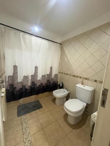 a bathroom with a toilet and a shower curtain at La Delfina in Chacras de Coria