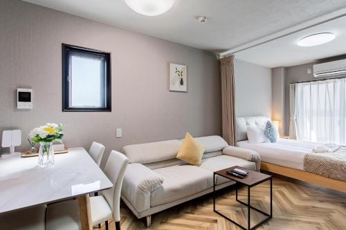 a living room with a couch and a bed at Hopetree NambaImamiya in Osaka