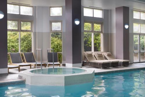 a large swimming pool with chairs and a tub in a building at DoubleTree by Hilton Dartford Bridge in Dartford