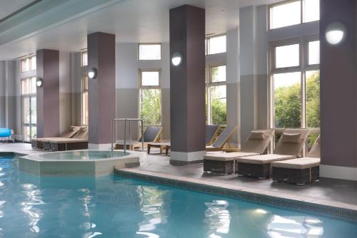 a pool in a hotel with chairs and a swimming pool at DoubleTree by Hilton Dartford Bridge in Dartford