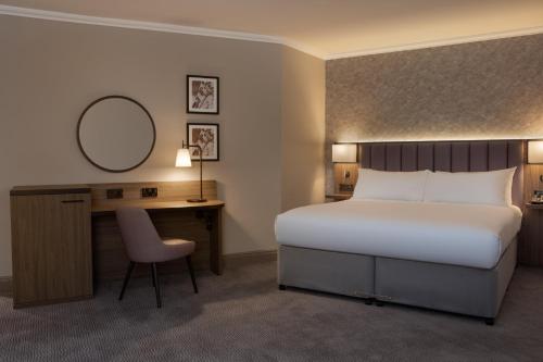 a bedroom with a bed and a desk and a mirror at DoubleTree by Hilton Dartford Bridge in Dartford