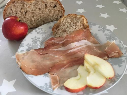 a plate of food with meat and bread and an apple at B&B Il Piccolo Principe room and breakfast in Bieno