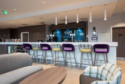 a bar with purple bar stools in a room at Hampton By Hilton Edinburgh West End in Edinburgh