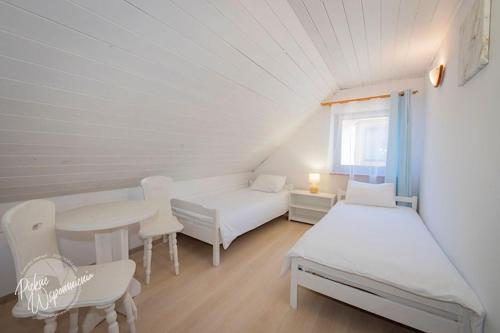 a room with two beds and a table and chairs at Comfortable holiday home, summer pool in Łeba