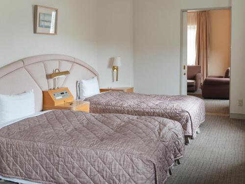 a hotel room with two beds and a chair at Takarazuka Washington Hotel in Takarazuka