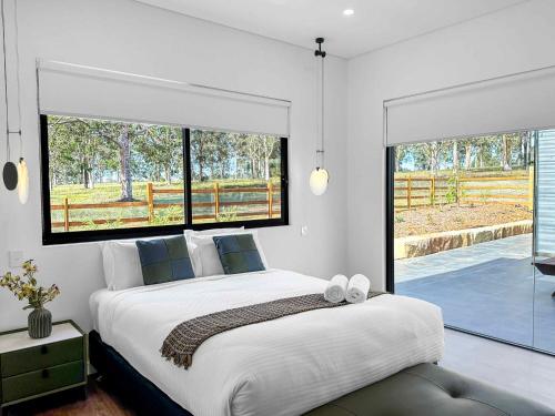 a bedroom with a large bed and a large window at Sereno in Pokolbin