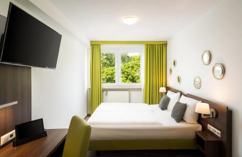 a hotel room with a bed and a flat screen tv at Arthotel ANA Eden Karlsruhe, Trademark Collection by Wyndham in Karlsruhe