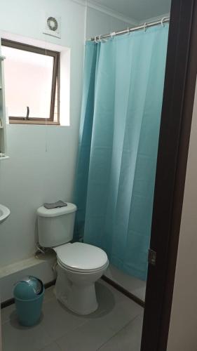 a bathroom with a toilet and a blue shower curtain at Casa Linares in Linares