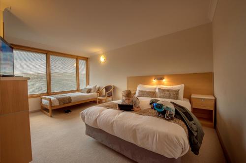 a small child sitting on a bed in a bedroom at Smiggins Hotel & Chalet Apartments in Perisher Valley