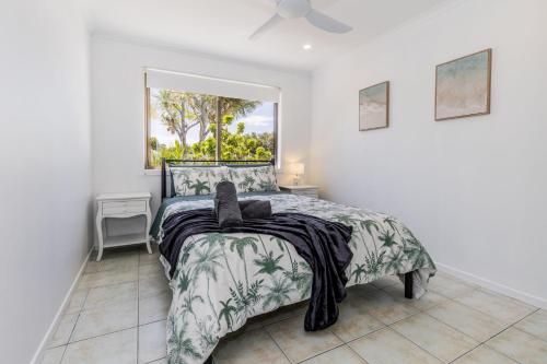 a bedroom with a bed and a window at Anchor and Palms in Agnes Water