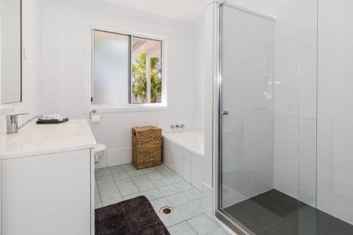 a white bathroom with a shower and a sink at Anchor and Palms in Agnes Water