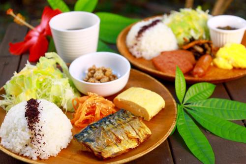 two plates of food with rice and vegetables on a table at ゲストハウス303 in Zamami