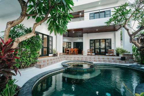 an indoor pool in front of a house with trees at Nipper Resort & Villa Nusa Dua in Ujung