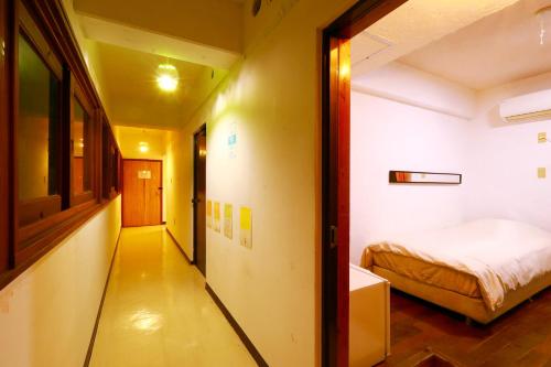 a small room with a bed and a hallway at ゲストハウス303 in Zamami