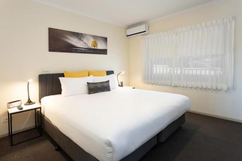 a bedroom with a large white bed and a window at Quest Tamworth in Tamworth