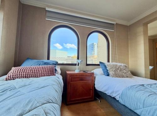 two beds in a room with two windows at Aragonés departamentos in Temuco