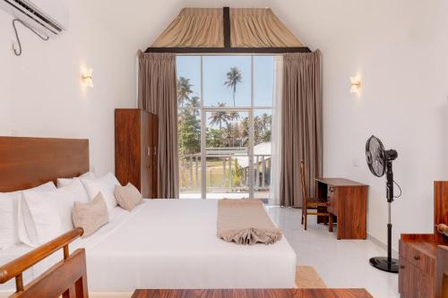 a bedroom with a bed and a large window at Madiha Beach Resort in Matara