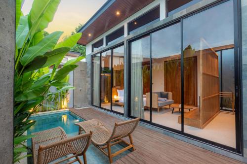 a house with a swimming pool and glass walls at Anasera Villas Echo Beach Canggu in Canggu