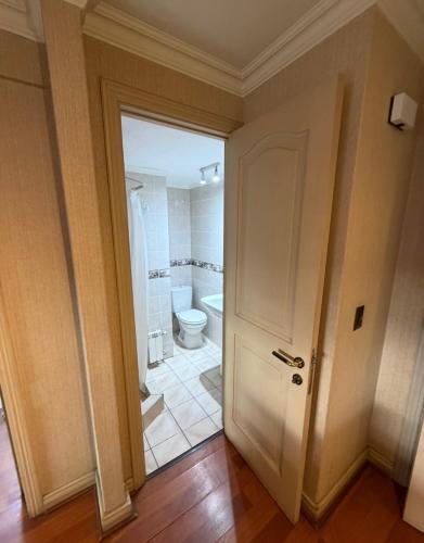 a bathroom with a white toilet and a door at Aragonés departamentos in Temuco