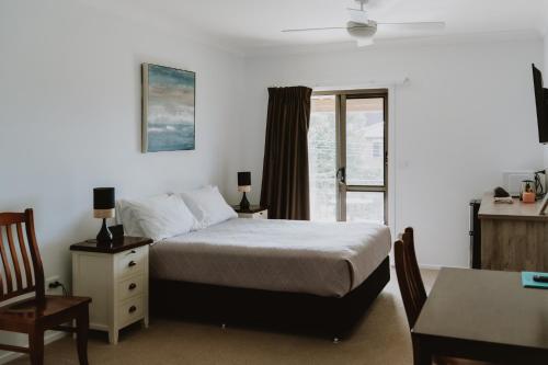 a bedroom with a bed and a desk and a table at Riverside Rest Nambucca Heads in Nambucca Heads