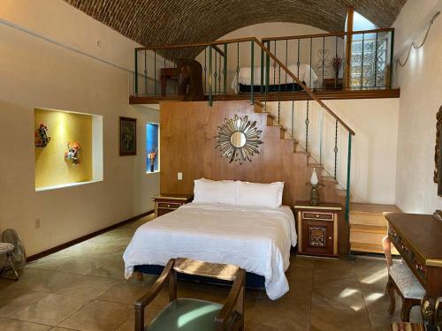 a bedroom with a bed and a spiral staircase at hotel la ermita suites in San Miguel de Allende