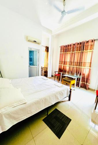 a bedroom with a white bed and a table at Sampath Grand Hotel in Mawanella